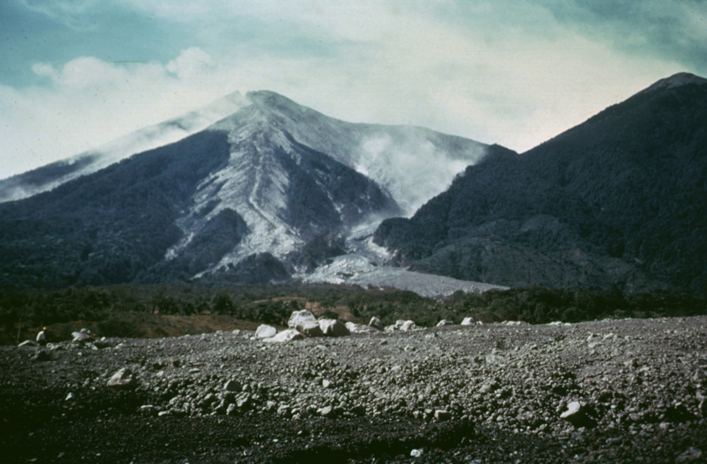 Hot pyroclastic flow deposits from the 1974 eruptions fill barrancas on the eastern flanks of Fuego. The deposit was the northeastern-most produced during the eruptions. Large blocks in the foreground were emplaced near the terminus of the deposit. The light-colored pyroclastic deposits extending from the summit are confined within levees with broader surge deposits that overtopped them. Photo by Greg Hahn, 1974 (courtesy of Bill Rose, Michigan Technological University).