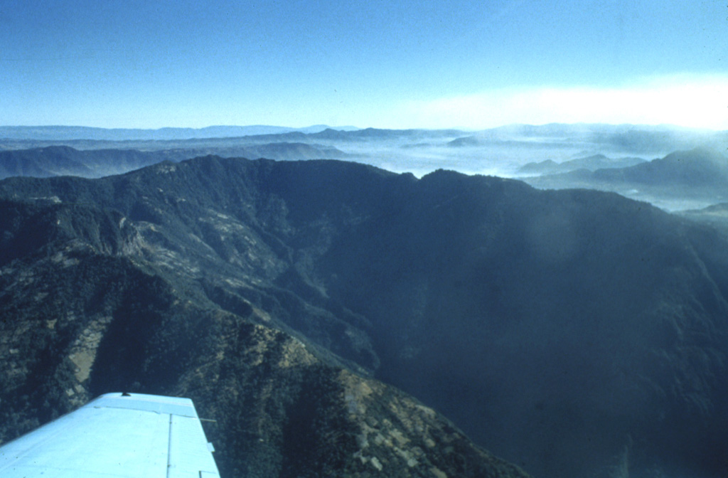 The southern side of Siete Orejas volcano is cut by a large breached caldera drained by the Ocosito river.  The caldera, seen here from the SW, is 3.5 km wide and more than 10 km long, and its walls tower about 1000 m above the caldera floor.  The origin of the caldera is uncertain, but may involve one or more processes including collapse following a major explosive eruption, collapse by slope failure, and excavation by headward stream erosion. Photo by Bill Rose, 1980 (Michigan Technological University).