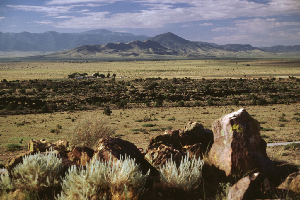 The dark-colored lava flow extending across the center of the photo is a lobe of the Carrizozo flow.  This view looks SE from the Valley of Fires recreation area administered by the Bureau of Land Management to the Sierra Blanca in the distance.  The recreation area lies on one of several kipukas of older rocks surrounded by the Carrizozo flow, which covers an area of about 330 km2. Photo by Lee Siebert, 1999 (Smithsonian Institution).
