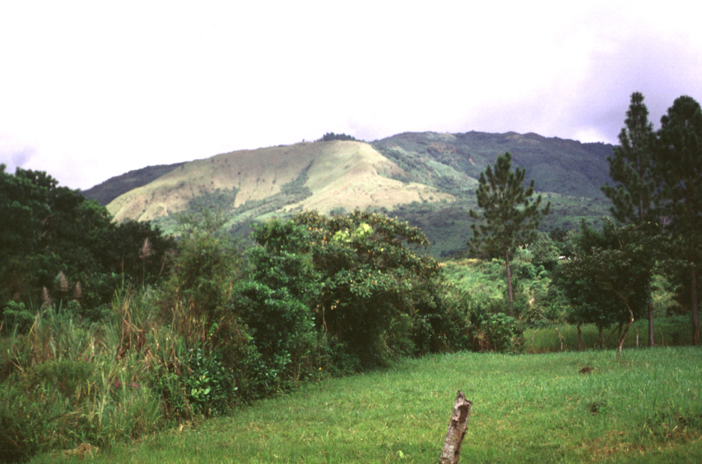 The grassy area in the sunlight at the left center is an explosion crater formed on the SW side of El Castillo volcanic horst, whose high point forms the right horizon.  The breached crater is one of the Quaternary vents formed during reactivation of the horst. Photo by Lee Siebert, 1998 (Smithsonian Institution).