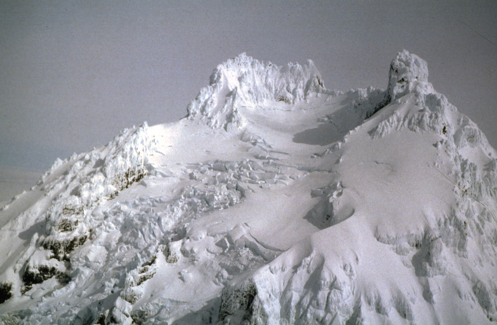 Glaciers descend the upper flanks of Isanotski between the summit pinnacles. Locally known as Ragged Jack, this is at the center of an E-W-trending group of three volcanoes on Unimak Island.  Photo courtesy of Alaska Volcano Observatory, 1994.