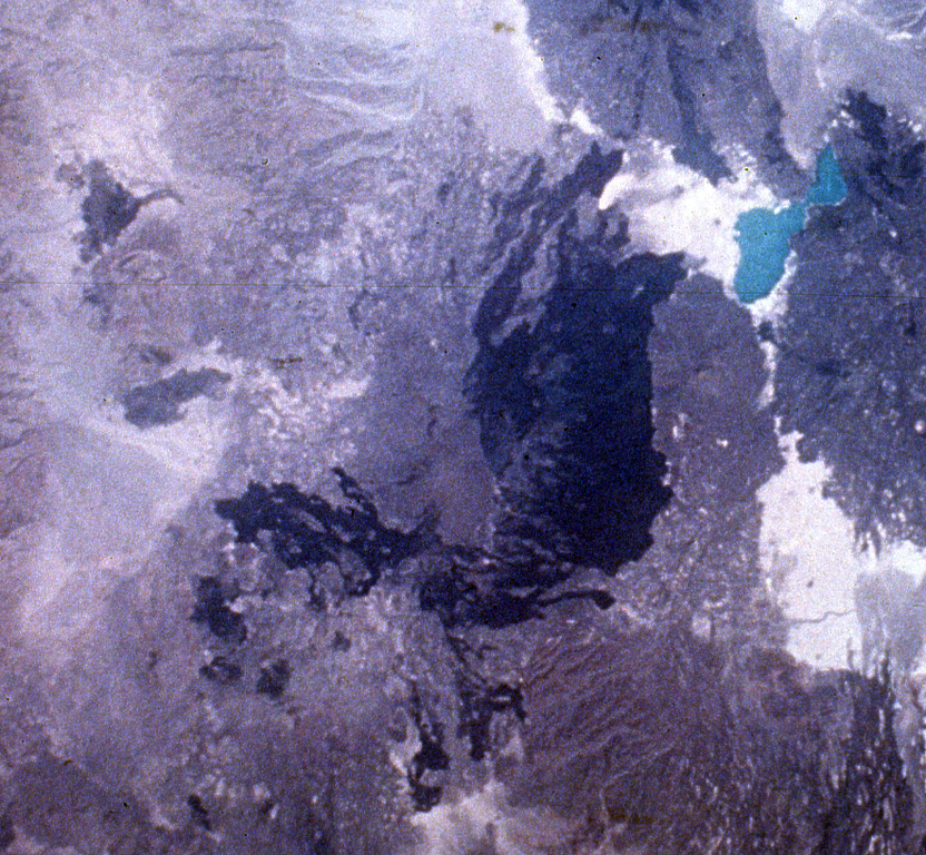 The massive Alayta shield volcano (center) covers an area of 2,700 km2 in the western Danakil depression SW of Lake Afrera (upper right). The volcanic consists of two parts--an elongated shield volcano on the west (medium-toned) and an extensive lava field forming the dark-colored area on the eastern flank of the shield volcano. The Alayta lava field, covered by very fresh lava flows (the most recent of which was erupted in 1907), was erupted from N-S-trending fissures and laps up against the western flank of Afderà volcano (immediately SW of Lake Afrera). NASA Space Shuttle image S-19-35, 1984 (http://eol.jsc.nasa.gov/).