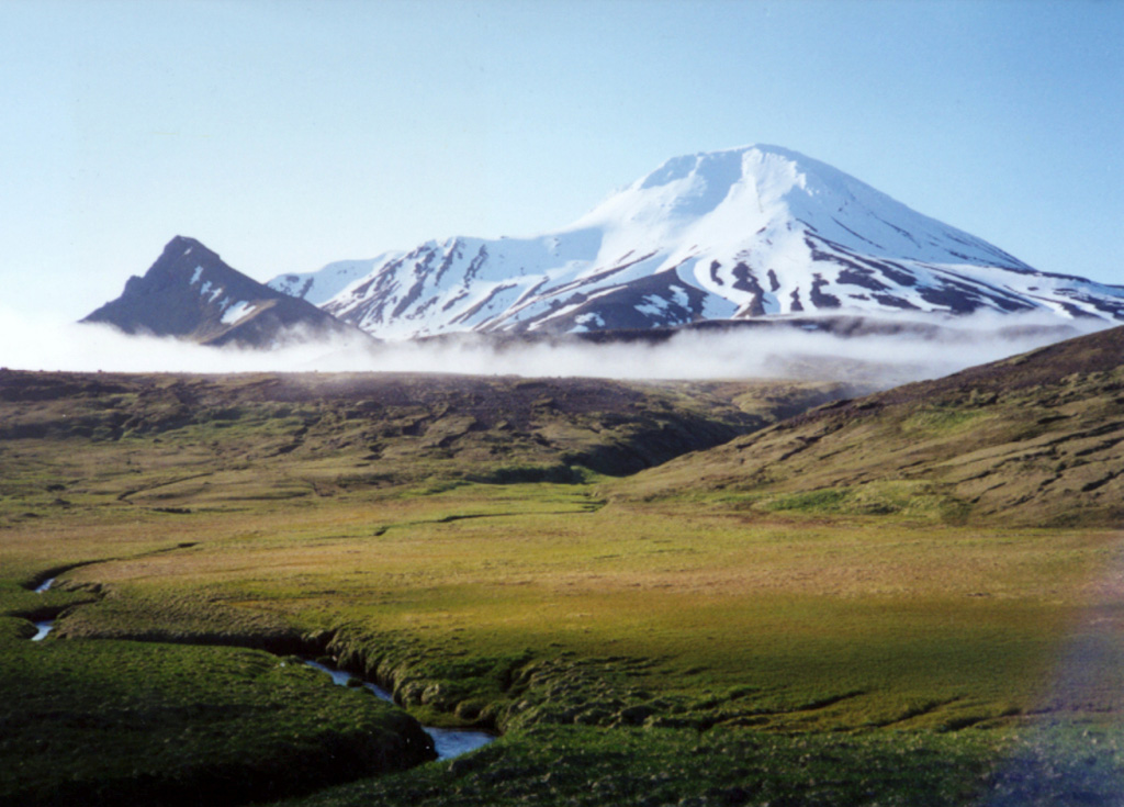 Little Sitkin is seen here on the NW of the island and the peak to the left is part of the Williwaw Cove Formation, consisting of Tertiary to Quaternary lava flows. Two nested calderas lie between this peak and Little Sitkin. An older Pleistocene caldera lies just beyond the cloud in the center. Photo by Steve Ebbert, 2000 (U.S. Fish and Wildlife Service).