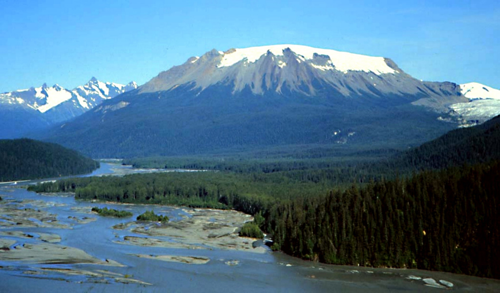 Hoodoo Mountain, as seen from the SE across the Iskut River in northwestern British Columbia, is a flat-topped stratovolcano. It has an ice cap 3 km in diameter and has had several episodes of subglacial eruptions. Most of the deposits are lava flows. The oldest eruptions of the volcano occurred about 100,000 years ago and the most recent eruptions about 9,000 years ago. This is one of the largest peralkaline volcanoes in the northern Cordilleran volcanic province. Photo by Ben Edwards, 1994 (Dickinson College, Pennsylvania).