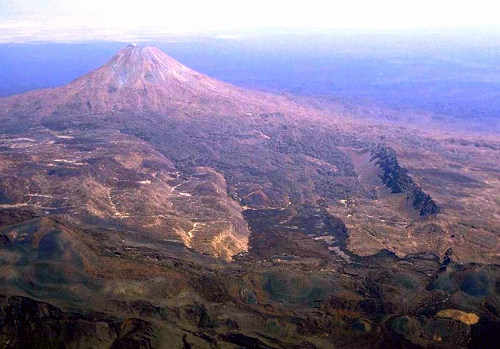 The steep-sided, conical Dalafilla volcano rises 300 m above surrounding lava fields of Alu volcano in the foreground in this view from the NW. This morphology, unusual for the Erta Ale Range volcanoes, results from the extrusion of viscous, silicic lava flows. These silicic flows extend primarily to the east from the 613-m-high summit. On the western side they are blocked by walls of a horst structure along the crest of the Erta Ale Range that forms the linear ridge in the right side of the photo. Copyrighted photo by Marco Fulle, 2002 (Stromboli On-Line, http://stromboli.net).