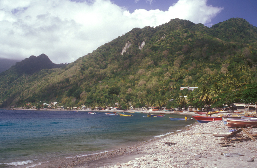 The Morne Patates (far left) and Crabier (right) lava domes, the youngest features of the Morne Plat Pays volcanic complex, rise above Scotts Head village on the southern tip of Dominica.  The youngest dated eruption from Morne Patates took place about 685 years Before Present (BP) and produced block and ash flow deposits.  Similar deposits were dated at about 1560 yrs BP, and an airfall deposit dated at about 2380 yrs BP also originated from this group of young lava domes.   Photo by Lee Siebert, 2002 (Smithsonian Institution).