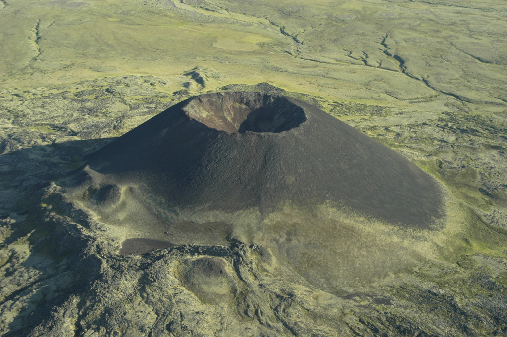 Scoria cones, such as Eve Cone on the flank of Edziza volcano, are formed by the explosive ejection of fragmental material that accumulated around the vent. This symmetrical cone is part of the Desolation Lava Field on the northern flank of Edziza and is one of the youngest features of the volcano. Basaltic lava flows erupted from the base of the cone, which reaches about 150 m high and has a 45-m-deep crater. Photo by Ben Edwards, 1995 (Dickinson College, Pennsylvania).
