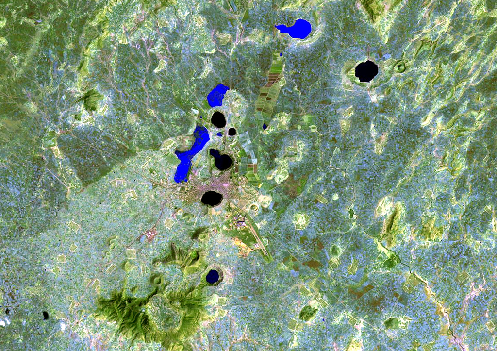 The Bishoftu volcanic field is a chain of lake-filled maars (dark-colored in this Landsat image), tuff cones, and scoria cones, lies along the Ethiopian Rift Valley. The city of Debre Zeit (left-center) lies between two maars, the irregular-shaped Lake Hora and the circular Lake Bishoftu. The Haro Maja tuff ring and its neighbor to the west, lake-filled Kilole maar (upper right), are offset to the east. NASA Landsat image, 1999 (courtesy of Hawaii Synergy Project, Univ. of Hawaii Institute of Geophysics & Planetology).