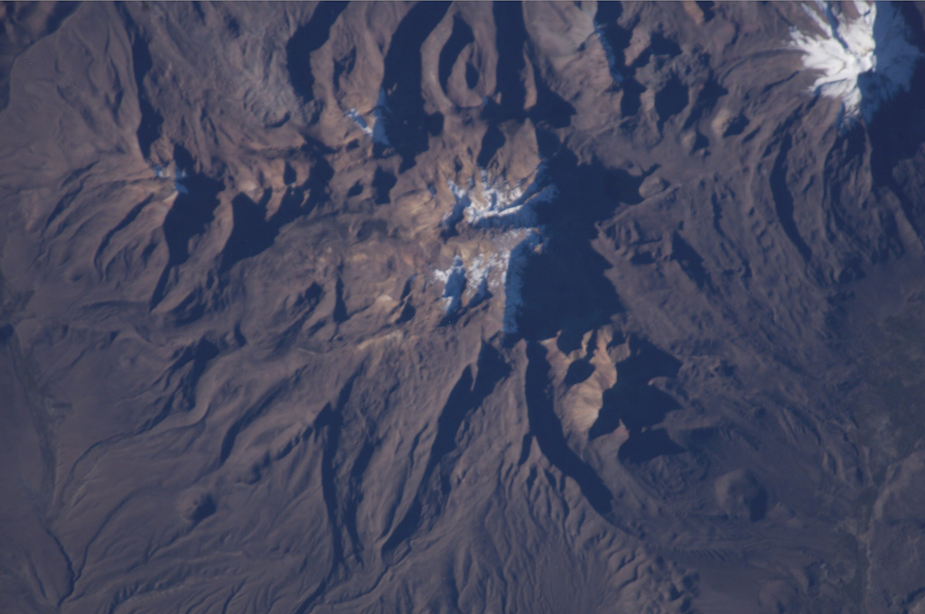 The snow-speckled volcanic complex near the center of this NASA International Space Station image (with north to the lower right) is the Patilla Pata complex. The age of this volcano is uncertain, and Holocene activity has not been confirmed. This extensively eroded andesitic and basaltic volcano lies along a graben extending NE from glacier-covered Pomerape volcano at the upper right, which is part of the Nevados de Payachata complex that includes Parinacota volcano. NASA International Space Station image ISS009-E-6839, 2004 (http://eol.jsc.nasa.gov/).