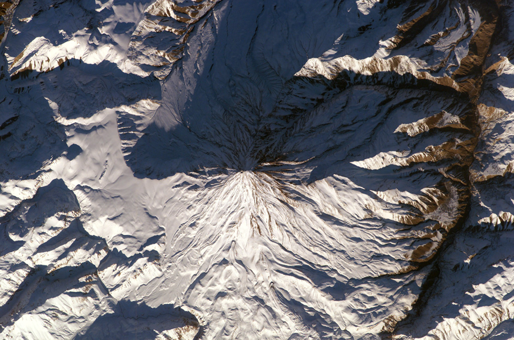 Winter snows highlight morphological features of Damavand volcano in this NASA International Space Station image (N to the upper left). Lava flows with prominent levees can be seen at the bottom of the image and a small well-preserved crater can be seen at the summit. The volcano is located about 80 km NE of the capital city of Tehran. NASA International Space Station image ISS010-E-13393, 2005 (http://eol.jsc.nasa.gov/).