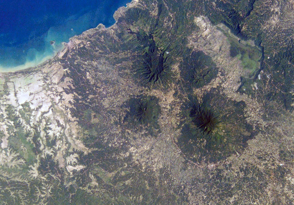 The small circular, forested volcano at the center of this NASA International Space Station image (N is to the top right) is Pulosari. The stratovolcano has a nearly 300-m-deep summit crater with fumaroles along its walls. The volcano lies SE of the 15-km-wide Pleistocene Danau caldera, whose northern and eastern rims and light-colored floor are visible at the upper right. NASA International Space Station image ISS004-E-10353, 2002 (http://eol.jsc.nasa.gov/).