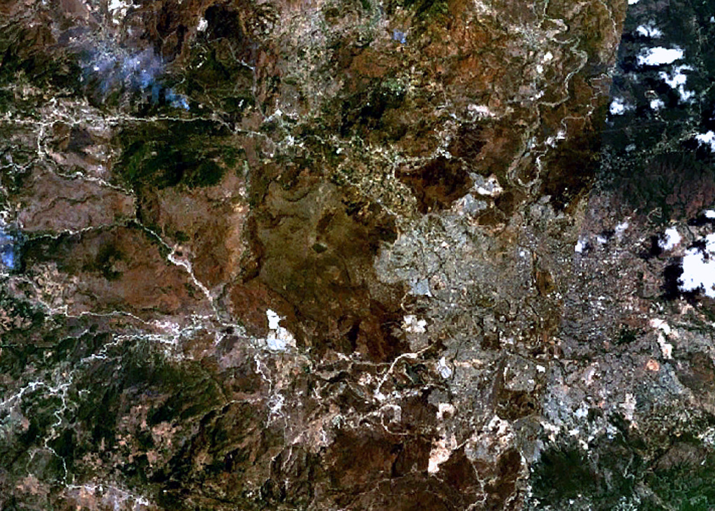 The volcano near the center of this NASA Landsat image (with north to the top) is El Pedregal, the most prominent Quaternary volcano in the highlands of central Honduras.  This low-angle basaltic shield volcano was constructed on a high plateau of Miocene ignimbrites immediately west of the capital city of Tegucigalpa, which covers much of the lower-right quadrant of this image.  Isolated remnants of basaltic lava flows from El Pedregal and separate vents occur over broad areas to the west and NW. NASA Landsat 7 image (worldwind.arc.nasa.gov)