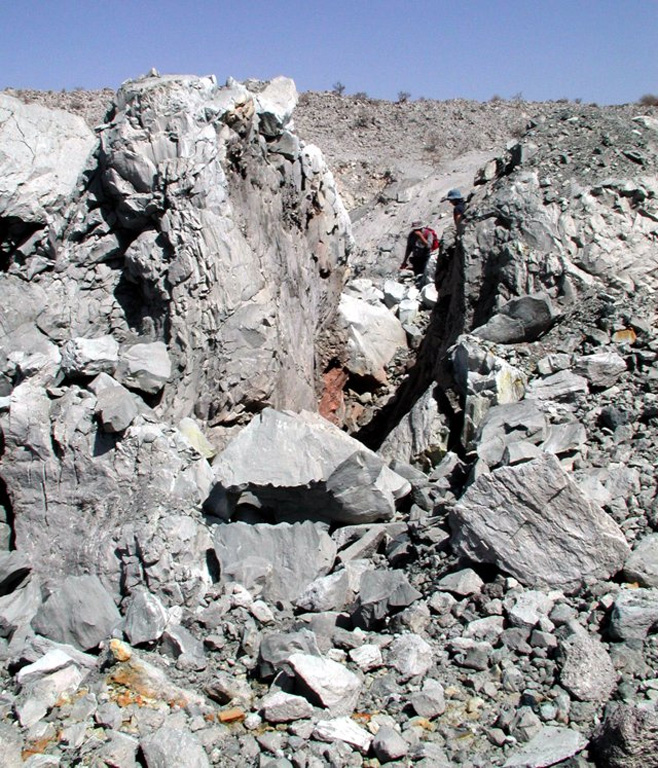 Geologists, seen here on 16 October 2005 at the upper right, walk along a fracture in a 30-m-wide dome formed during the September 2005 eruption of Dabbahu volcano. Curving fractures in the top of the new dome are viewed from the south. The dome, not mantled by tephra, was emplaced at the end of the brief eruption in September. Photo by Anthony Philpotts, 2005 (University of Connecticut).
