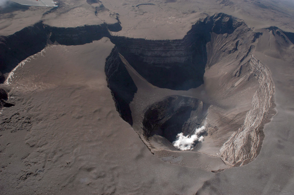 This 19 April 2005 aerial photograph of the Karthala Chahalé crater was taken from the SE. The surface of the lava lake, which had been emplaced the day before, had chilled and was emitting a white plume. Much of the summit area displays recently-deposited tephra from explosive eruptions on the 16th and 17th. Photo by Nicolas Villenueve, 2005 (Université de la Réunion).