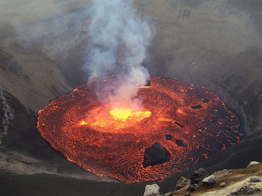An explosive eruption on 24-25 November 2005 deposited ash over the SE and SW parts of Grand Comore Island in the Indian Ocean (also known as Ngazidja Island). Ashfall occurred in Moroni, the capital city of the Comoros, located on the W-central coast. On 26 November this incandescent lava lake was observed inside Chahalé crater within the summit caldera of Karthala volcano. Within a few days the surface of the 60-80-m-wide lava lake had mostly solidified, and the eruption ended on 8 December. Photo by Christophe Roche, 2005.