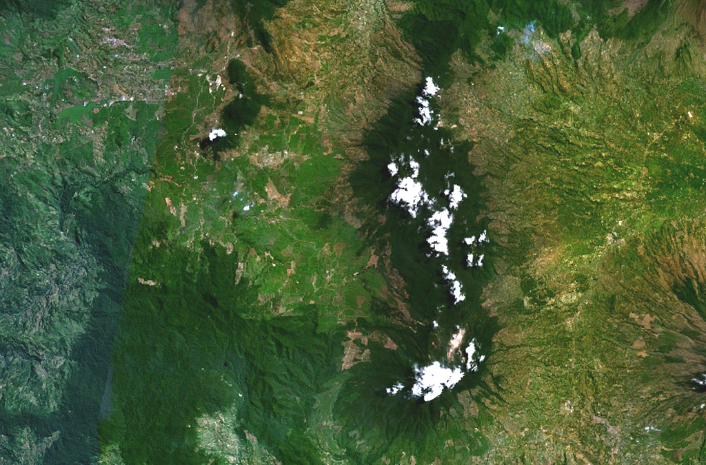 Kendang volcano is the partially cloud-covered dark green area at the right-center of this composite NASA Landsat image of central Java (with north to the top). The stratovolcano contains major geothermal areas. The latest eruptions produced a very young rhyolitic lava dome and obsidian lava flows. Kendang lies immediately north of Papandayan volcano (the cloud-covered area at the bottom right-center) and SE of Wayang-Windu volcano (the elongated dark-green area at the upper left-center). NASA Landsat 7 image (worldwind.arc.nasa.gov)