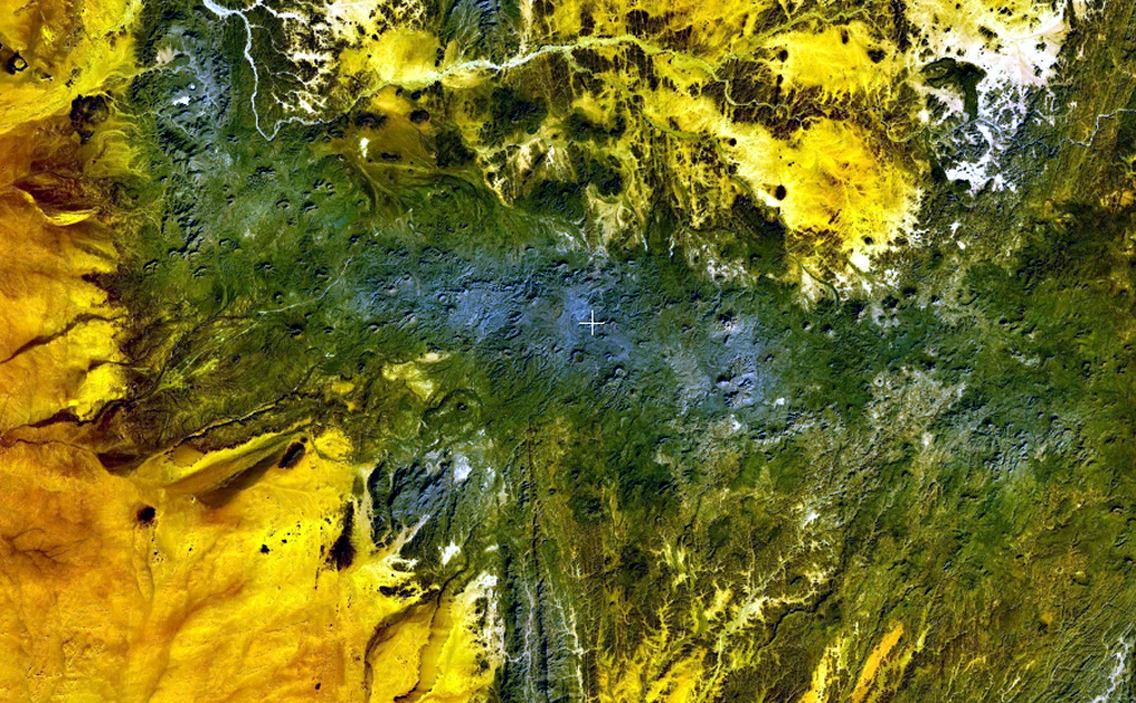 The dark-green and bluish-gray areas extending across this NASA Landsat false-color image depict the elongated, E-W-trending Tahalra volcanic field, which covers an area of about 1,800 km2 in the Hoggar Province of southern Algeria. About 100 small basaltic cones formed during the Pliocene and Pleistocene, and the most recent activity during the late-Pleistocene and Holocene, produced about 20 maars and cones along the northern margin of the volcanic field. NASA Landsat 7 image (worldwind.arc.nasa.gov)