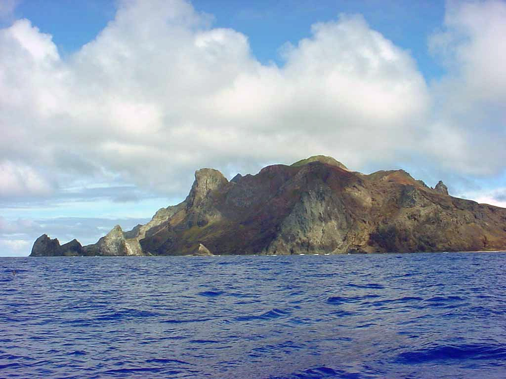 The rugged coast of the small island of Trindade reflects dissection of numerous phonolitic lava domes and steep-sided volcanic plugs.  Trindade lies at the eastern end of an E-W-trending chain of submarine volcanoes and guyots extending about 1100 km from the continental shelf off the Brazilian coast. The youngest volcanism, at Vulcao de Paredao on the SE tip of the island, constructed a pyroclastic cone with lava flows that reached the sea. Anonymous photo (commons.wikimedia.org/wiki/Image:Trindade-035.jpg).