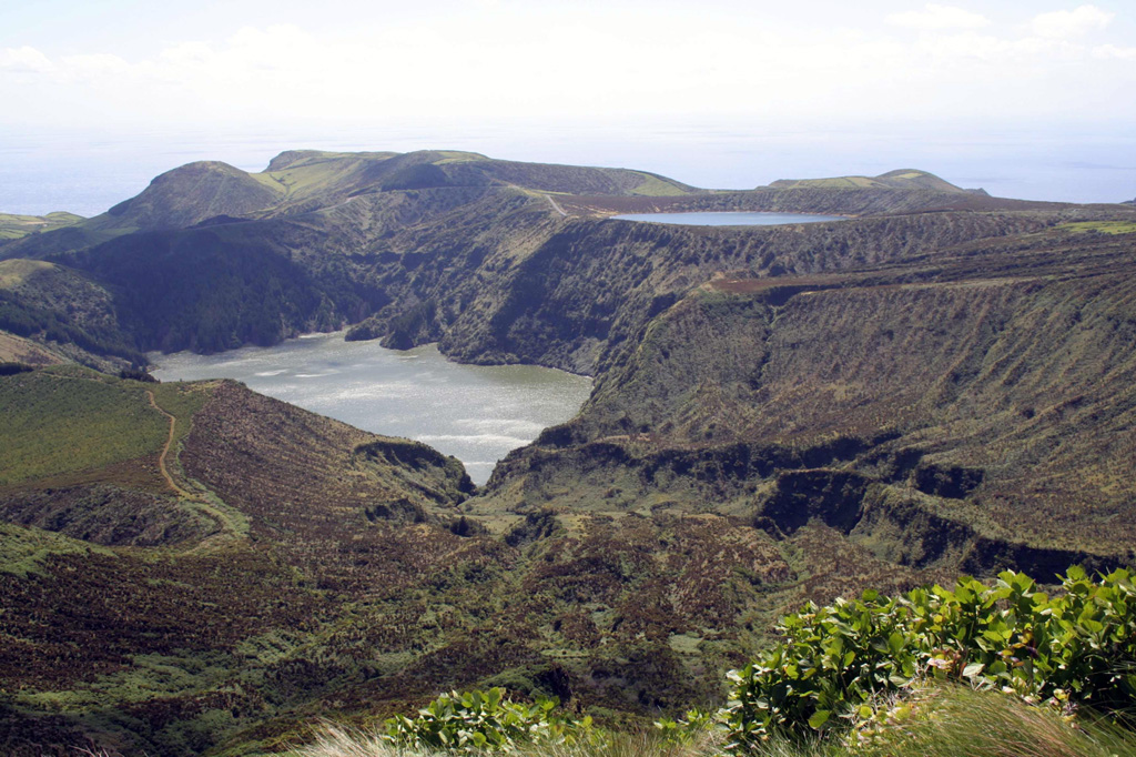 Lakes occupy Caldeira Funda (left) and Caldeira Rasa (right) on SW Flores Island in this view from the east. The Caldeira Funda de Lajes tuff ring formed about 3,150 years ago, accompanied by a lava flow that reached the coast to the southeast. The 12 x 17 km island of Flores has numerous cones and craters. Photo by Björn Ehrlich, 2007 (Wikipedia).