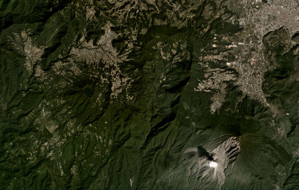 The large scarp of Siete Orejas is down the center of this November 2020 Planet Labs satellite image monthly mosaic (N is at the top; this image is approximately 21 km across). Seven peaks surround the scarp, which likely formed during flank collapse towards the south. The city of Quetzaltenango is NE and Santa María volcano is SE, with a gas plume rising from the Caliente Dome. The Volcan Chicabal is on the SW flank, containing Chicabal Lake. Satellite image courtesy of Planet Labs Inc., 2020 (https://www.planet.com/).