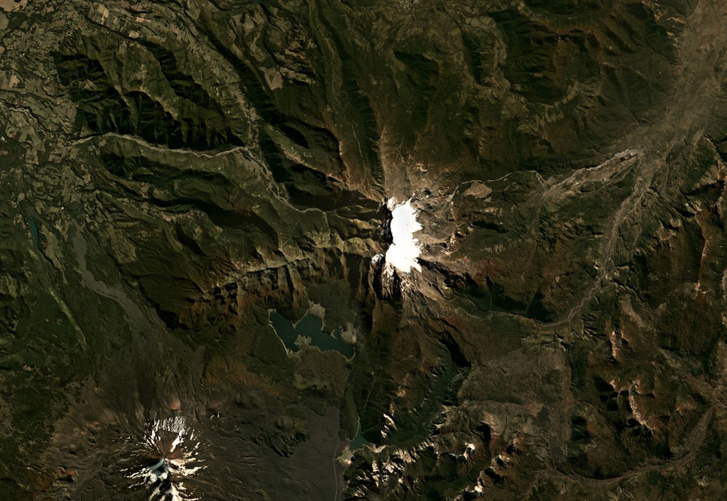 The late-Pleistocene Sierra Nevada in Chile has a N-S oriented glaciated ridge and a 7-km-long E-W alignment of fissure vents in the center of this Planet Labs satellite image monthly mosaic (N is at the top; this image is approximately 40 km across). Steep cliffs on the western side expose the stratigraphy of the summit area. Satellite image courtesy of Planet Labs Inc., 2019 (https://www.planet.com/).