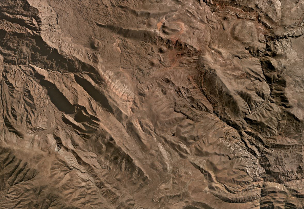 This July 2020 Planet Labs satellite image shows some of the southern Huambo volcanic field (in this monthly mosaic N is at the top; image is approximately 26 km across). Near the top of the image, the western cone is Marbas Grande with a 470-m-wide summit crater. East of that are three cones: Marbas north of the ridge then Marbas Chico I and Marbas Chico II south of the ridge. Around the cones are their lava flows.  Satellite image courtesy of Planet Labs Inc., 2020 (https://www.planet.com/).