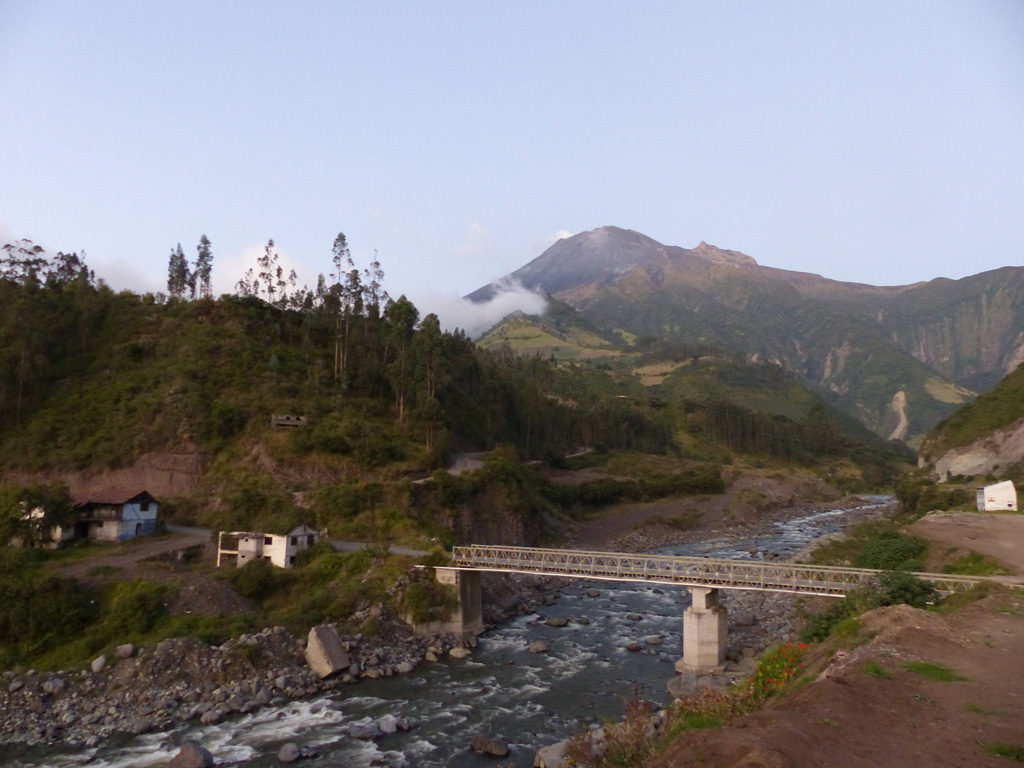 The NE flank of Tungurahua is seen here on 4 December 2015 from the town of Palictahua, near the Iglesia Católica de Cristo del Consuelo. Lahars at Tungurahua frequently travel large distances and occasionally cause road closures around the volcano. The foreground shows a large concrete block in front of the existing bridge that may be remains of an older damaged structure. Photo by Ailsa Naismith, 2015.
