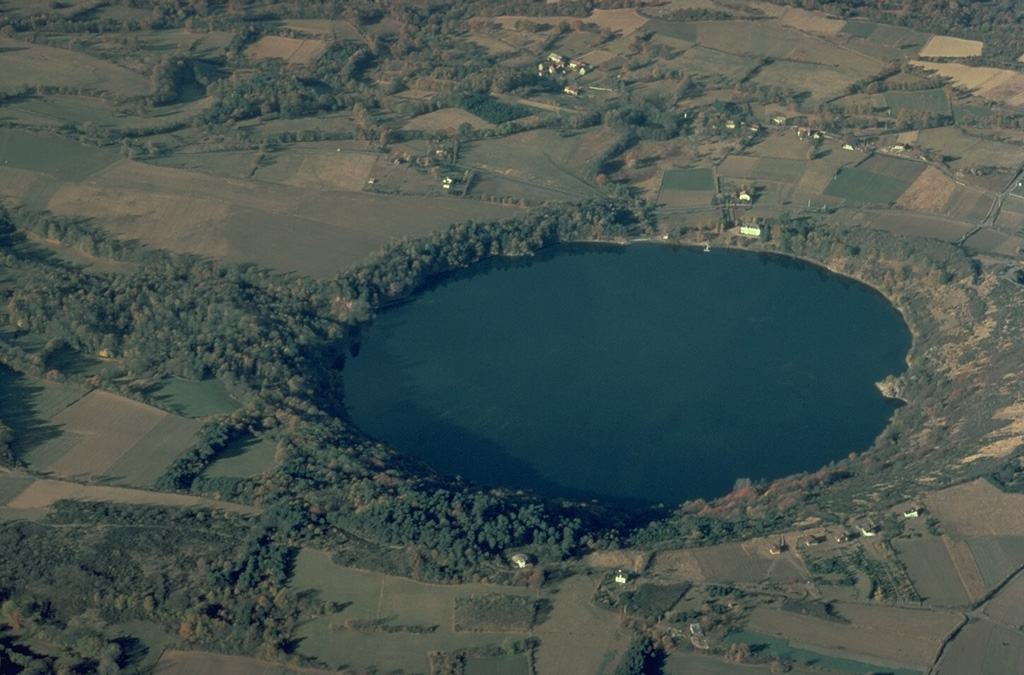 The Gour de Tazanet maar is the northernmost volcano of the Chaîne des Puys volcanic field in central France.  The lake-filled explosion crater, one of many maars in the volcanic field, was formed when magma came in contact with groundwater.  Rhythmic ejection of fragments of nonvolcanic rock produced bedded ash deposits and formed a low-rimmed crater, 700-m wide and 66-m deep. Copyrighted photo by Katia and Maurice Krafft.