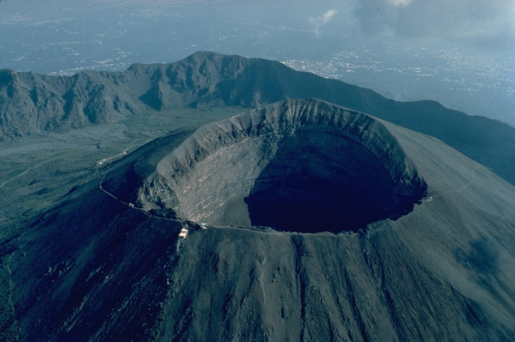 Volcanic craters are depressions above a volcanic vent that form as a result of explosive eruptions or collapse.  Craters can form at the summit of a volcano or on its flanks.  Their sizes and shapes vary widely.  Some, like this 600-m wide, 300-m deep crater of Italy's Vesuvius volcano, are large and deep, and have steep-sided walls.  Other craters, such as maars and tuff rings produced by powerful explosions involving water-magma interaction, are often much wider than they are deep.  Vertical-walled pit craters form by collapse over an eruptive fissure.  Copyrighted photo by Katia and Maurice Krafft, 1982.