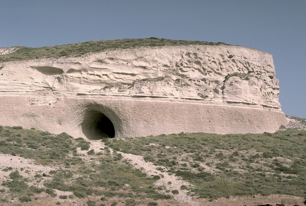 The course of the Minoan eruption of Santorini is recorded in this roughly 10-m-thick exposure of deposits produced by the 3,500-year-old eruption. The loosely-compacted basal pinkish layer is composed of early pumice deposited from powerful vertical eruption plumes. It is overlain by lighter-colored, laminated pyroclastic surge deposits that were produced when water was incorporated into the eruption column as caldera collapse began. The thicker, upper unit consists of pyroclastic flow deposits. Photo by Lee Siebert, 1994 (Smithsonian Institution).