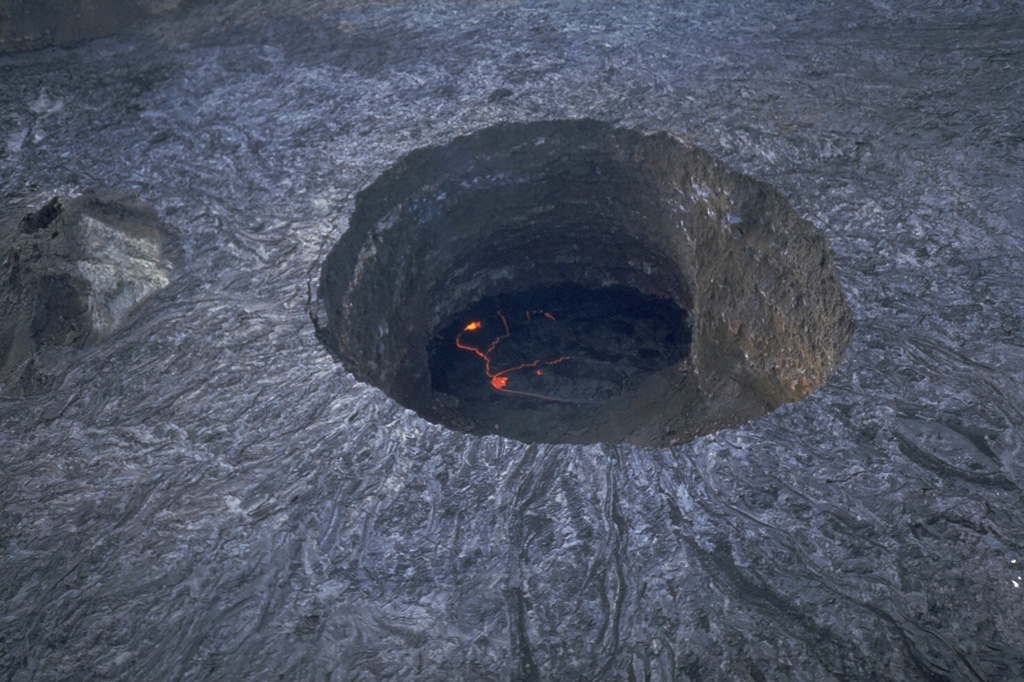 The 100-m deep southern pit crater cuts the floor of the summit crater of Ethiopia's Erta Ale volcano. This November 1992 photo shows an active lava lake at the base. Fresh lava flows radiate away from the crater rim. They were produced by lava overflows from the crater, particularly during 1971-73. The southern pit crater has had an active lava lake since at least 1967, and possibly since 1906. Few observations are made of this remote volcano, located in the extremely hot and arid Afar region. Photo by Luigi Cantamessa, 1992 (courtesy of Pierre Vetsch).