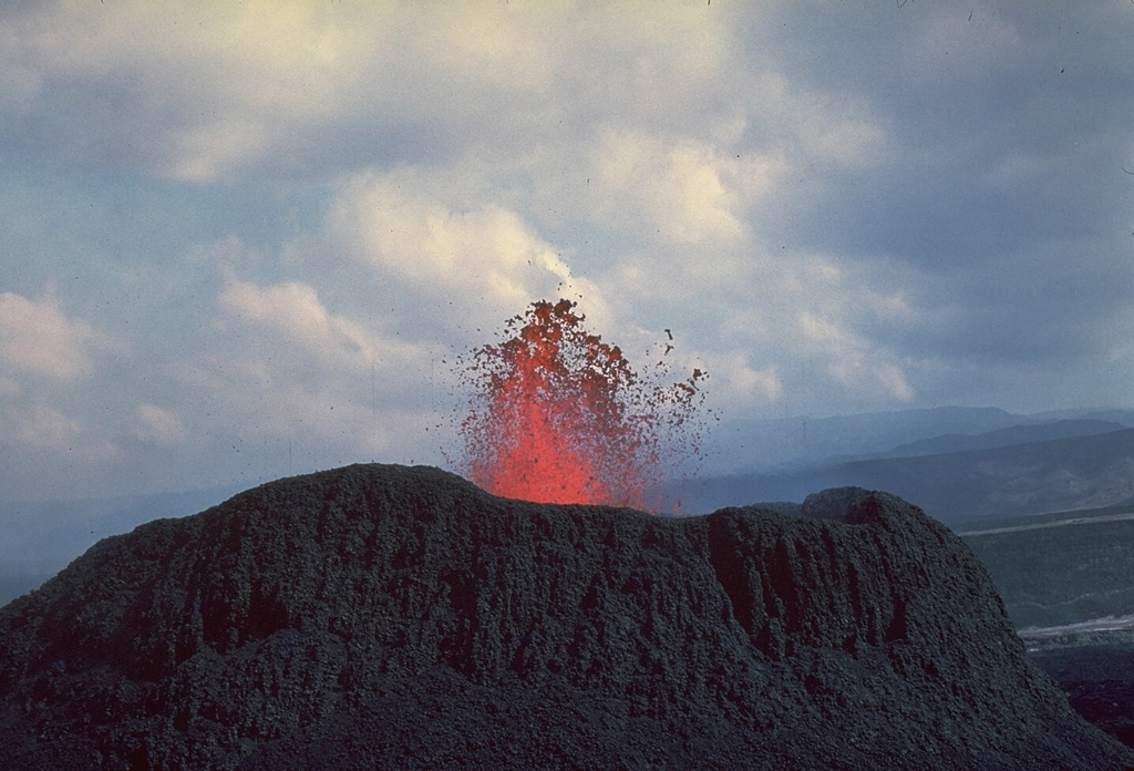 A small cinder cone ejects spatter during the first historical eruption of the Ardoukôba (Asal) Rift, which took place November 7-14, 1978.  Lava fountaining occurred from a 500-m-long fissure.  Several spatter cones and a cinder cone were formed along the fissure, which fed lava flows that covered about 3 km2 of the rift floor.  Copyrighted photo by Katia and Maurice Krafft, 1978.