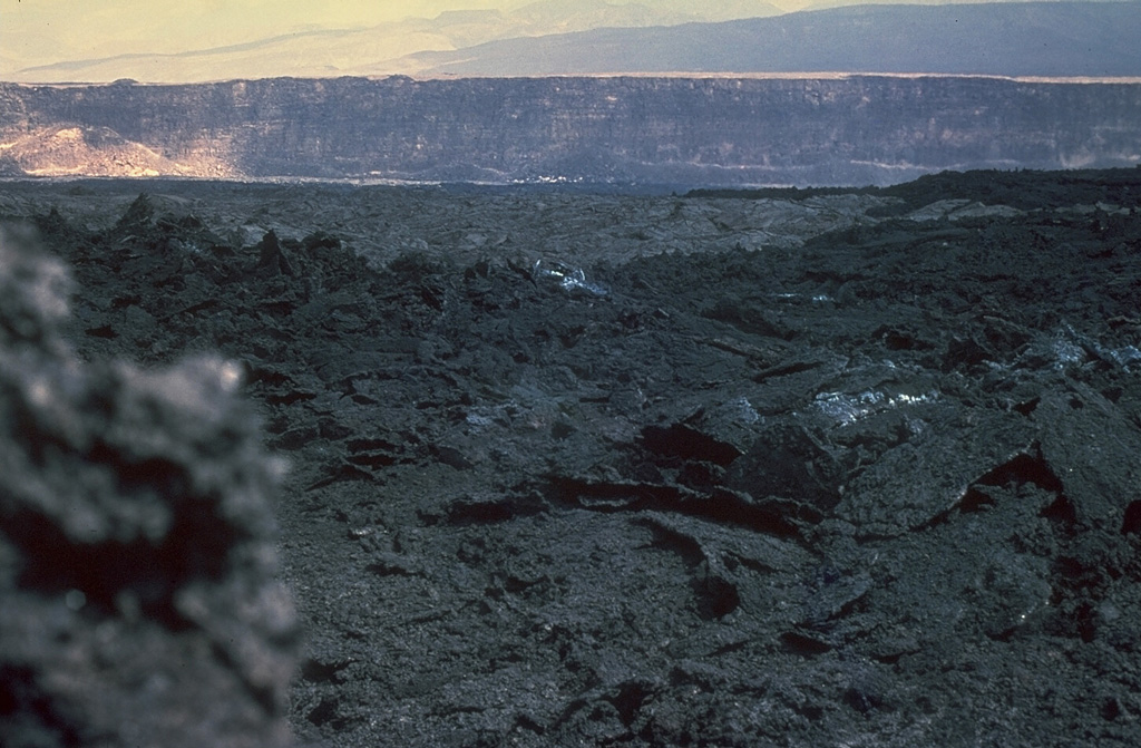 The dark aa lava flow in the foreground was produced during an eruption on the Arkdoukôba Rift November 7-14, 1978.  This photo from the SW looks across the rift during the eruption and shows one of the regional NW-SE-trending faults of the rift in the background.  Lava flows from the 1978 eruption covered about 3 km2 of the rift floor, primarily on the north side of the eruptive fissure. Copyrighted photo by Katia and Maurice Krafft, 1978.