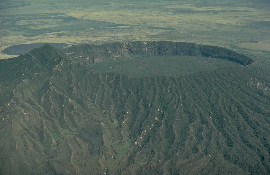 The trachytic Longonot stratovolcano SE of Lake Naivasha contains an 8 x 12 km caldera.  A large central cone, seen here from the SW, was constructed within the caldera and forms the summit of the volcano.  It is truncated by a circular, 1.8-km-wide caldera.  Post-caldera lavas erupted onto its floor give it a flat surface.  Masai tradition records a lava flow on the northern flank during the 19th century.  Similarly youthful-looking lava flows occur on the SW flank.    Copyrighted photo by Katia and Maurice Krafft, 1976.