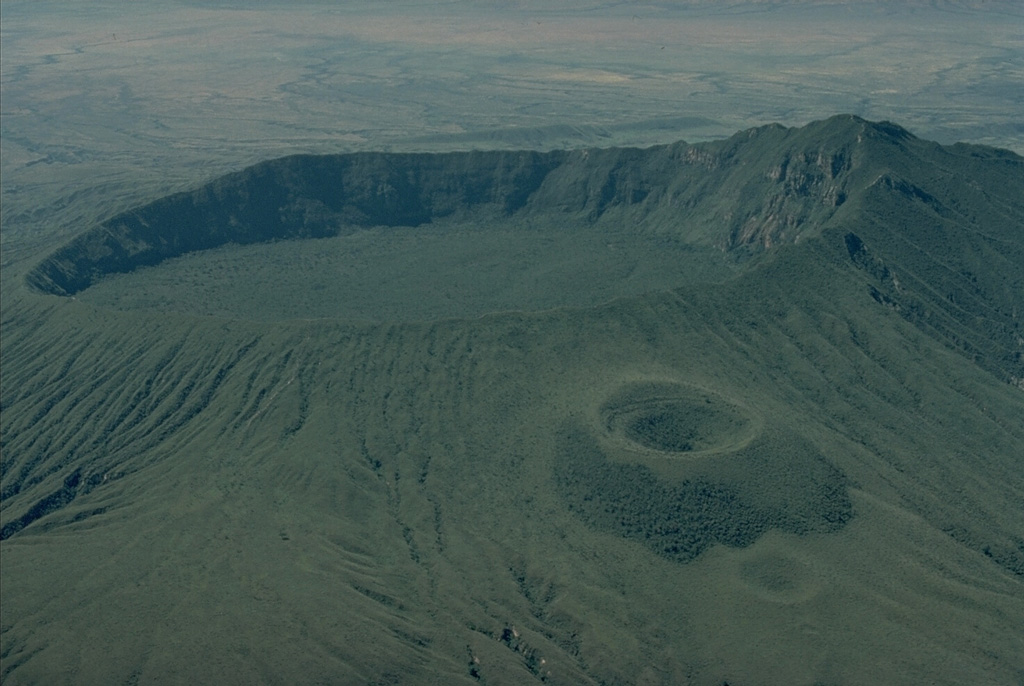 The small summit caldera of Longonot volcano is seen here from the NNE.  A circular crater tops a symmetrical cone erupted along a N-S fissure on the upper flanks of Longonot.  Fissures lower on the north flank produced the youngest eruption of the volcano during the 19th century.   Copyrighted photo by Katia and Maurice Krafft, 1976.