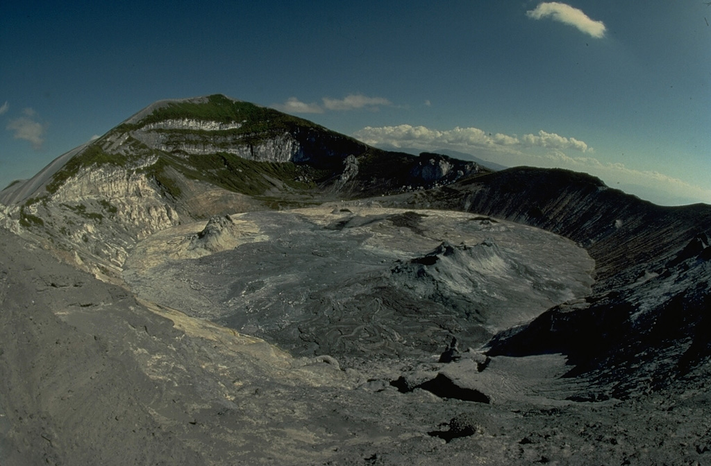 The north crater of Ol Doinyo Lengai, seen here from its NE rim in July 1988, has been the source of all historical eruptions from the volcano.  The second crater is located on the other side of the summit peak.  A decade-long eruption beginning in 1983 produced a series of lava flows on the floor of the crater.  By December 1988 lava had overflowed into a shallow depression below and to the right of the summit. Copyrighted photo by Katia and Maurice Krafft, 1988.