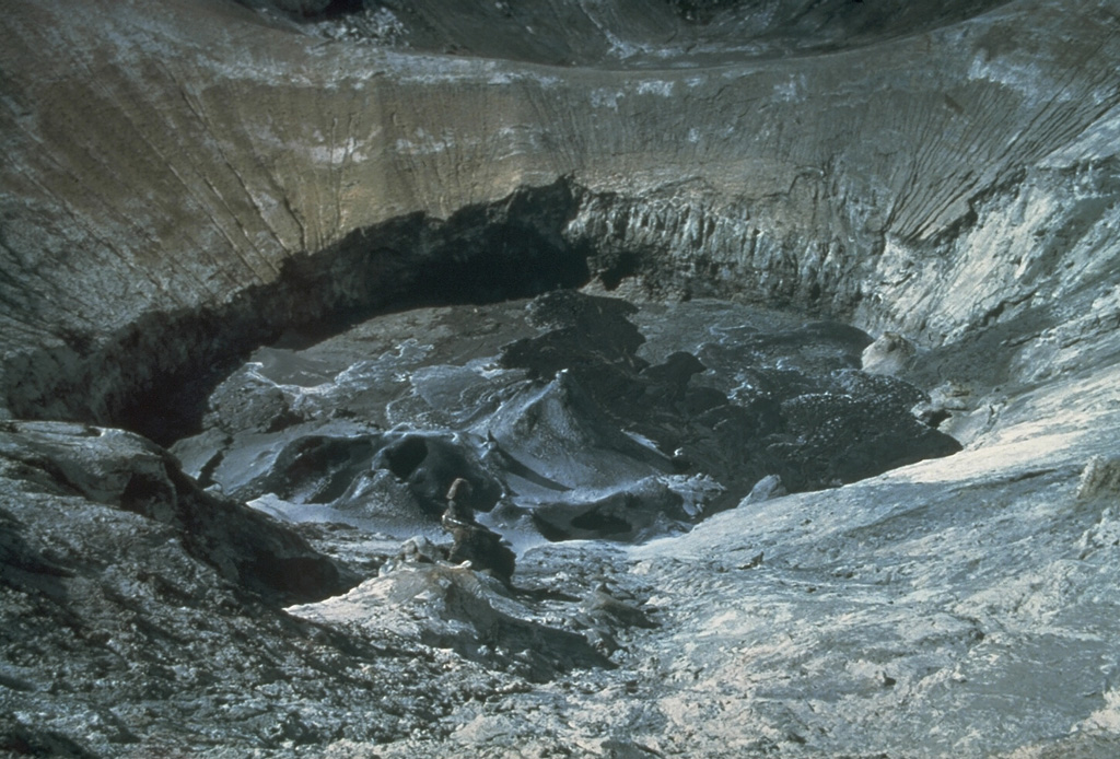 This June 1984 view looking southward across the north crater shows a fresh black lava flow and small spatter cones on the crater floor. This photo was taken early during the eruption episode that began in January 1983 and shows the considerable depth of the crater at the time. Continued emission of lava flows filled the crater to the level of the saddle at the top of the image by December 1988, at which time lava overflowed the rim into a shallow depression. Photo by Fred Trott, 1984 (courtesy of Celia Nyamweru, Kenyatta University).