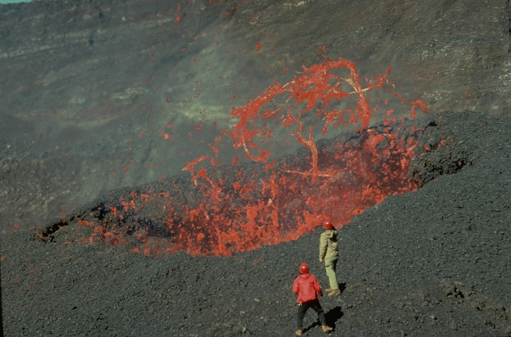 Red-hot ribbons of molten lava hurled above a vent in the Dolomieu summit crater of Piton de la Fournaise volcano in November 1975 are observed at close range by volcanologists Maurice Krafft and Jean-Claude Vallée.  These mild eruptions in the summit crater preceded more voluminous lava effusion from flank vents that lasted until April 1976. Copyrighted photo by Katia and Maurice Krafft, 1975.