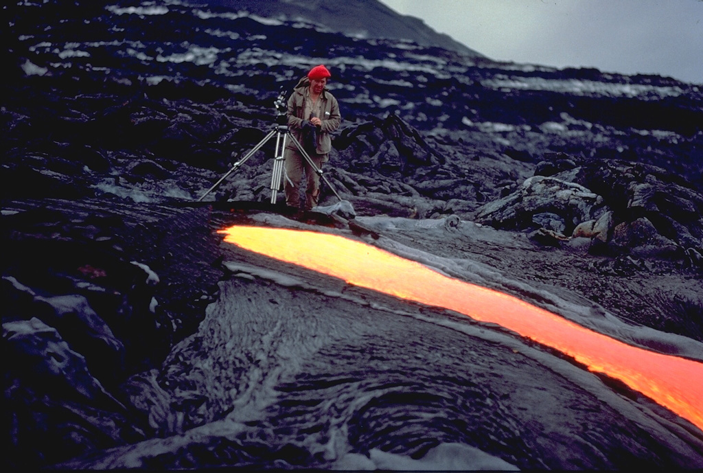 Volcanologist Maurice Krafft photographs a narrow lava flow on Piton de la Fournaise volcano in March 1976, his tripod only a meter away from the incandescent flow margin.  Maurice and Katia Krafft observed more eruptions than any other volcanologists, devoting their careers to documenting both the beauty of volcanoes and their hazards.  Before losing their own lives in 1991 filming pyroclastic flows on Unzen volcano, they produced videos that alerted officials and the public to the hazards of volcanoes, saving many other lives.  Copyrighted photo by Katia and Maurice Krafft, 1976.