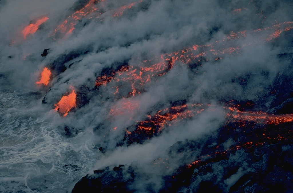 Steam clouds pour from an incandescent lava flow entering the Indian Ocean on March 25, 1986.  This flow, part of a long-term eruption during 1985-88, originated on March 23, 1986 from vents located at less than 100-m altitude.  This eruption was one of only six historical eruptions at Piton de la Fournaise volcano to originate from vents on the outer flanks. Copyrighted photo by Katia and Maurice Krafft, 1986.