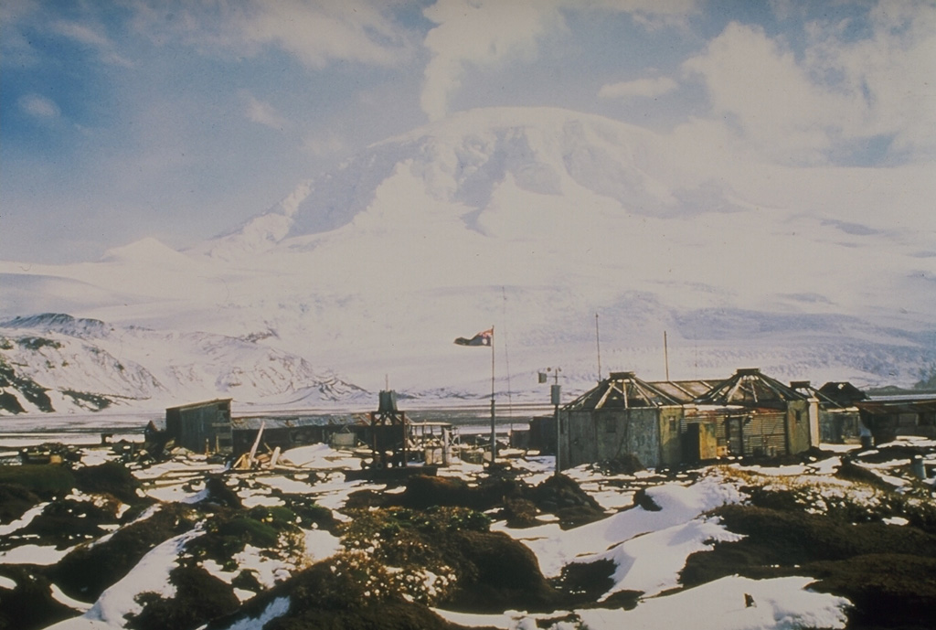 A plume rises in 1985 or 1986 from the summit of Big Ben volcano on Heard Island in the southern Indian Ocean. It is seen here from an abandoned Australian geophysical station at Atlas Cove, NNW of the summit. The historically active Mawson Peak forms the island's high point and lies within a 5-6 km wide caldera breached to the SW side of Big Ben. Small satellite scoria cones are mostly located on the N coast. Several subglacial eruptions have been reported. Photo by A. Hitchman, 1985 (courtesy of Wally Johnson, Australian BMRGG, Canberra).