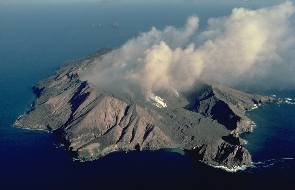 Steam and ash clouds rise from the crater of White Island, one of New Zealand's most active volcanoes, in this 1986 view from the SW.  The small, uninhabited 2 x 2.4 km wide island is the summit of a largely submerged volcano 50 km offshore from the coast of North Island.  The volcano contains two overlapping craters 0.4 x 1.2 km wide that have been the source of frequent intermittent moderate steam-and-ash eruptions since the beginning of historical observations in 1826.   Copyrighted photo by Katia and Maurice Krafft, 1986.