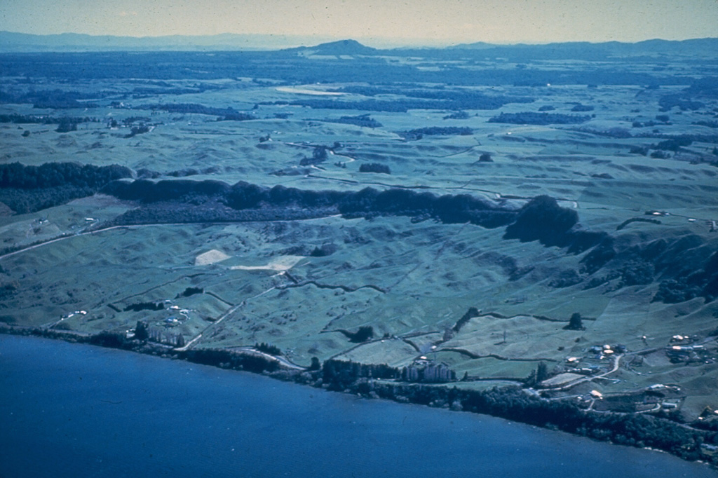 The northern margin of the 17-km-wide Rotorua caldera is defined by the dark line of trees along the cliff at the center of the photo. A succession of terraces marking former lake levels can be seen on the shore of Rotorua Lake. Rotorua is the NW-most of a cluster of calderas forming the Taupo Volcanic Zone in the central North Island. Photo by Lloyd Homer (courtesy of Bruce Houghton, Wairakei Research Center).
