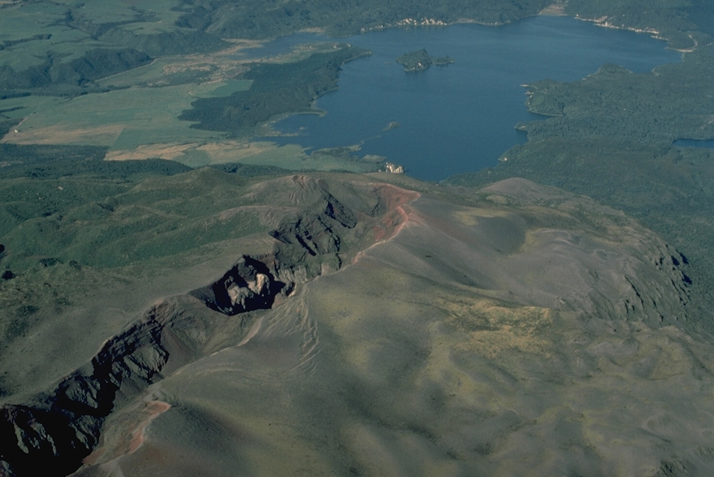 Eruptive fissures can follow the direction of regional faults, such as this New Zealand fissure that cuts diagonally across the photo.  The 8-km-long fissure continues beneath the lake and was the source of a major explosive eruption in 1886 from Tarawera volcano.  Most commonly, fissure vents extend radially down the flanks of a volcano from its summit.  In some cases, circumferential fissures open around the rim of a volcanic caldera. Copyrighted photo by Katia and Maurice Krafft, 1986.