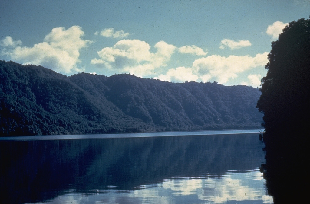 The Haroharo volcanic complex is the NW-most of two lava dome complexes forming the Okataina Volcanic Centre. A 16 x 28 km wide caldera was formed incrementally during eruptions between 300,000 and 50,000 years ago. Its rim, seen in this photo across the caldera lake, is generally obscured by a group of overlying lava domes. All post-caldera domes are less than 20,000 years old, and the most recent Haroharo eruption took place about 3,500 years ago. Photo by Ian Nairn (Geological Survey of New Zealand).