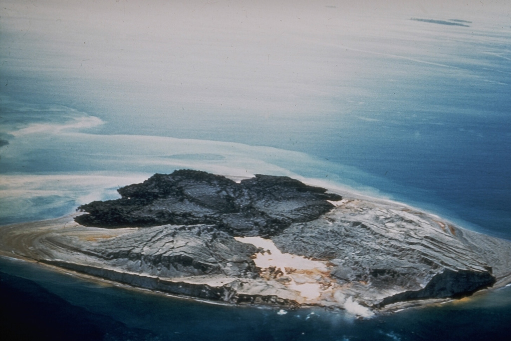 Intermittent submarine explosive and effusive eruptions from multiple vents during June 1953 to January 1957 created new islands that coalesced to form Tuluman Island. Activity was most vigorous during February-March 1955, and near the end of the eruption in January 1957 when subaerial effusive activity dominated. This March 1960 view from the SW shows dark rhyolitic lava flows at the far end of the island and lighter deposits from eroded tuff cones. Photo courtesy of Wally Johnson, 1960 (Australia Bureau of Mineral Resources).
