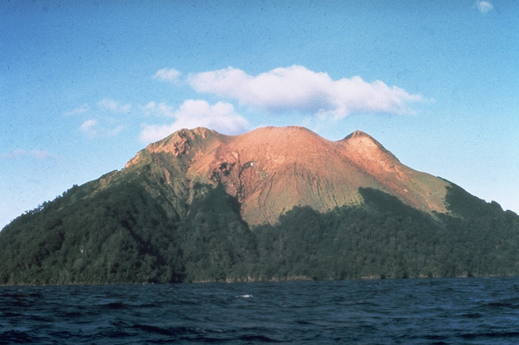The small 2.4 x 1.6 km island of Bam, seen here from the S, is the summit of a mostly submerged volcano that is one of the more active in Papua New Guinea. A 300-m-wide and 180-m-deep summit crater is source of recent eruptions, which have resulted in the sparsely-vegetated area. A younger cone (center) formed inside a SE-facing landslide scarp. Eruptions recorded since 1872 involved small-to-moderate explosive activity from the summit crater. Photo by Wally Johnson, 1970 (Australia Bureau of Mineral Resources).