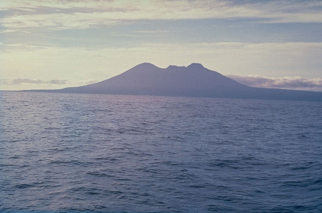 The broad profile of Long Island, seen here from the E, is composed of two steep-sided edifices, Mount Reaumur to the north (center) and Cerisy Peak to the south. Collapse of the volcanic complex during at least three major explosive eruptions about 16,000, 4,000, and 300 years ago produced a large 10 x 12.5 km caldera, whose low rim appears at the right. Photo by Russel Blong, 1976 (Macquarie University).