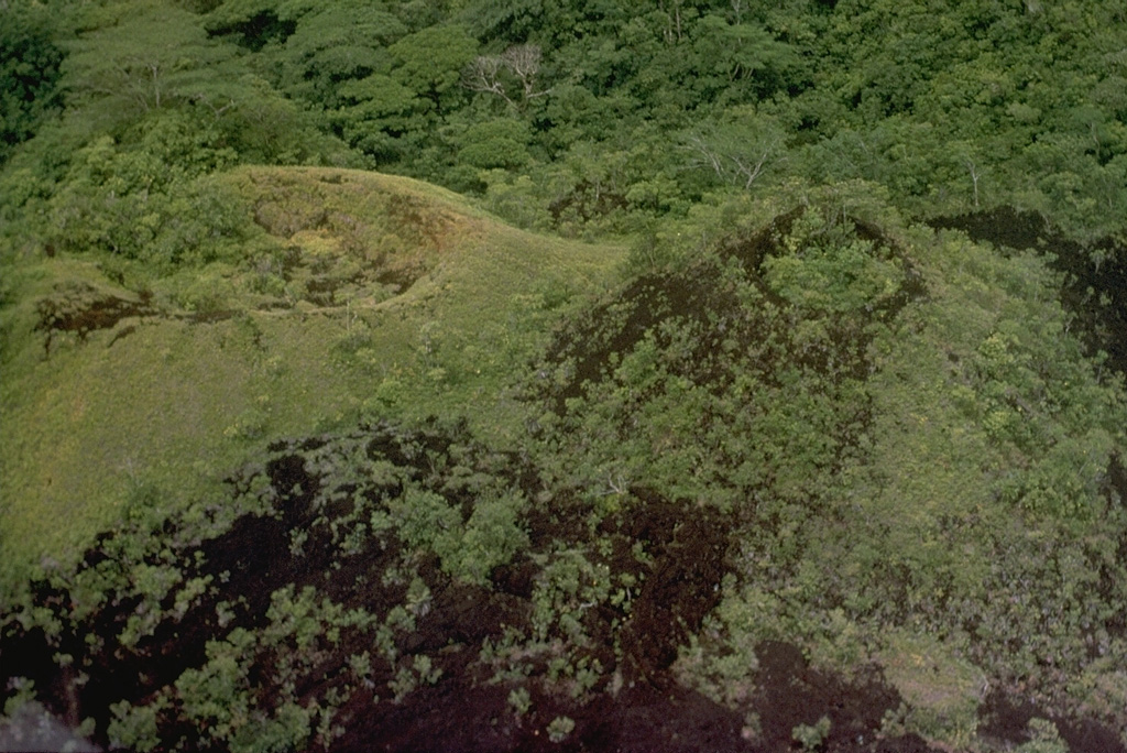 The youngest-known eruption of Dakataua caldera produced these cones on Mount Makalia, probably during the 1890s. The vent to the right in this image produced a lava flow that is only partly vegetated and descends the E flank of Mount Makalia. The cones are located along a N-S-trending chain of scoria cones and maars across the 12-km-wide caldera lake. Photo by Russell Blong, 1988 (Macquarie University).