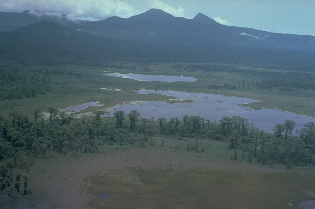 Pago, the flat-topped peak on the center horizon, is a young post-caldera edifice that may have been constructed less than 350 years ago within the 5.5 x 7.5 km Witori caldera. Extensive pyroclastic flows accompanied caldera formation about 3,300 years ago. The low-angled outer slopes of Witori, seen here from the S, consist primarily of pyroclastic flow and airfall deposits produced during a series of five major explosive eruptions from about 5,600 to 1,200 years ago. Photo by Russell Blong (Macquarie University).